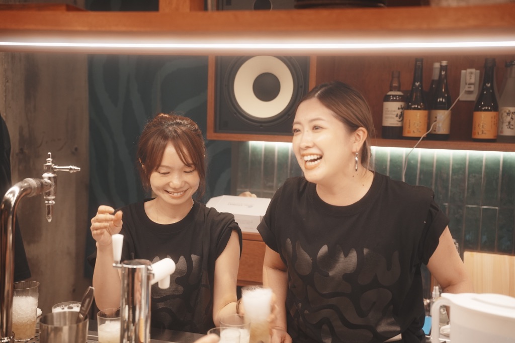 殻やぶりのスタッフ2名がビールを注ぎながら笑顔で対応